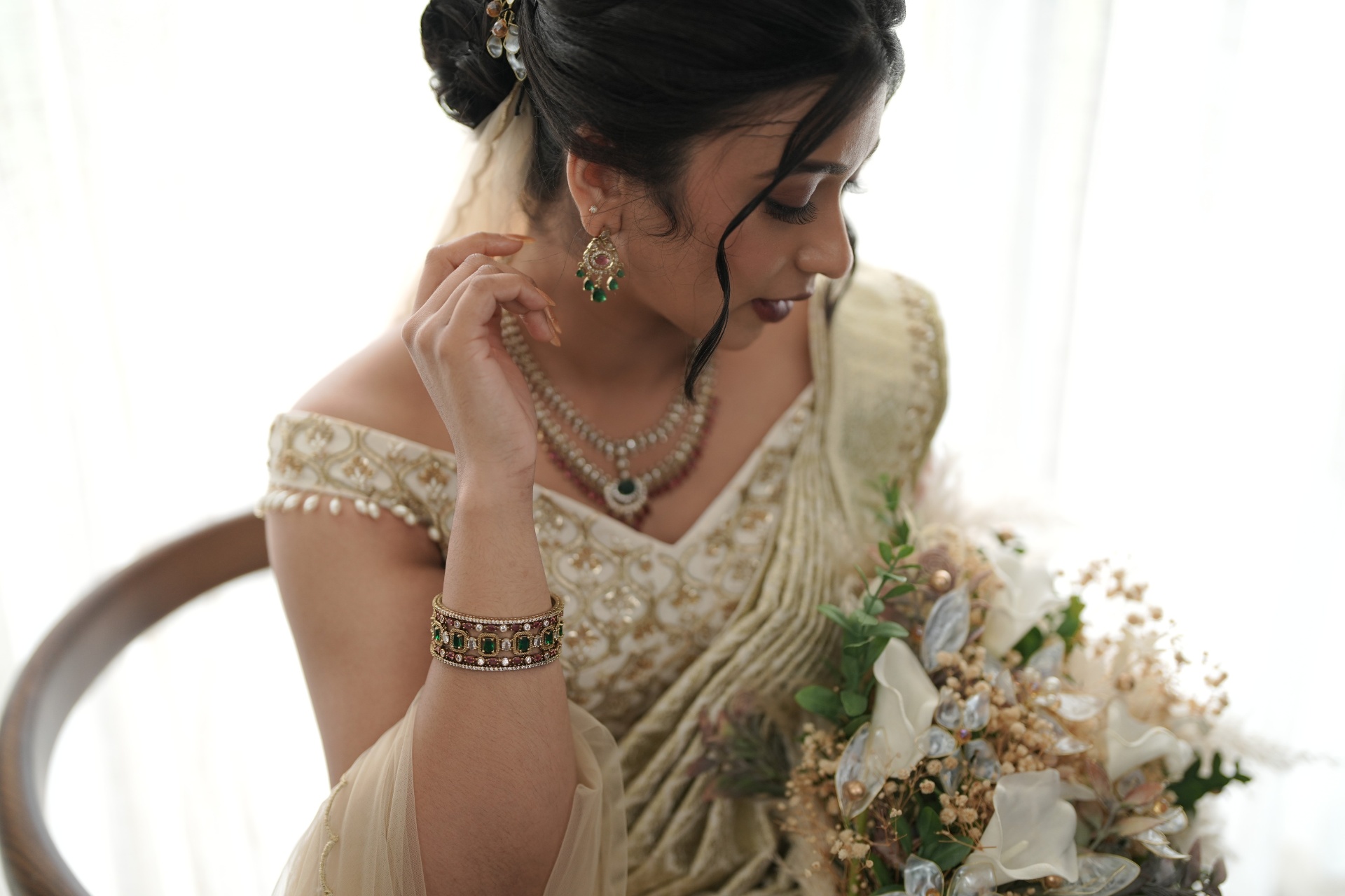 Bride in ivory saree with in house jewellery, holding bouquet