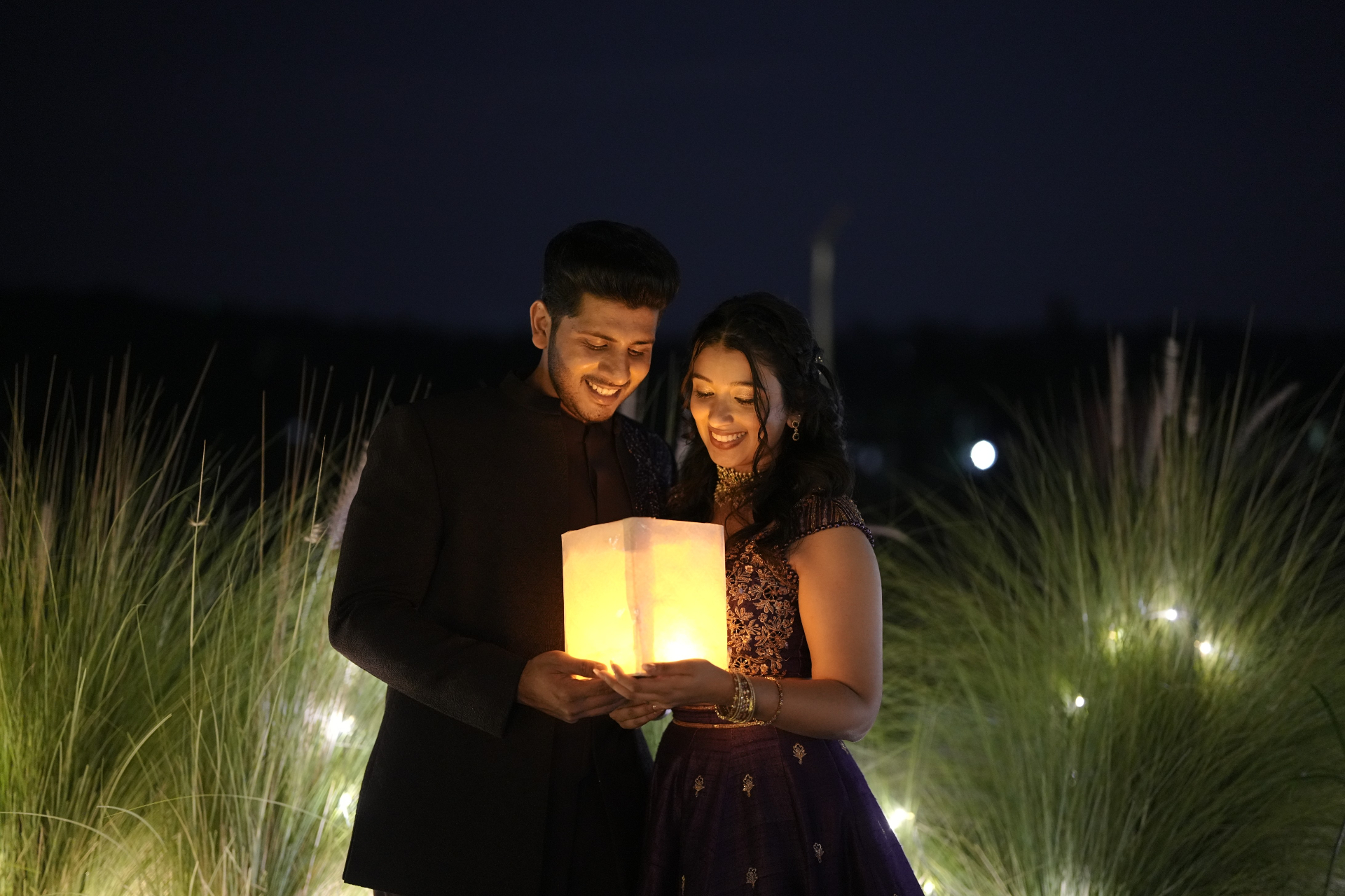 Alisha and Febin holding a lantern beneath the night sky
